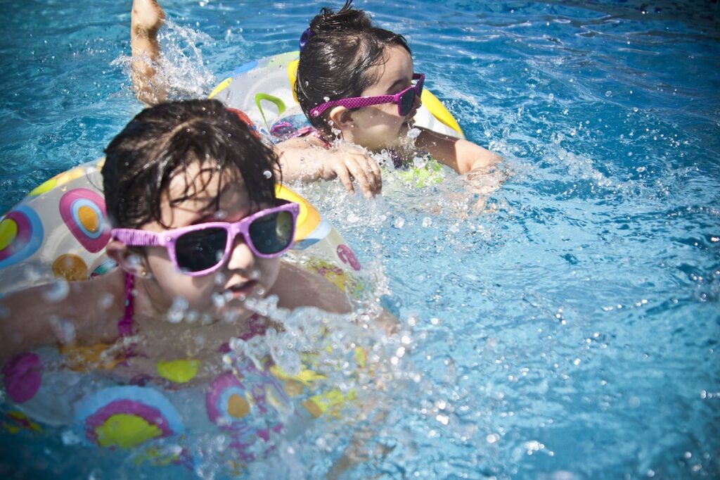 プールで浮き輪を使って泳いでいる子供二人の写真
